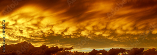 Sky on fire, panoramic view on sunset cloudscape in orange colors