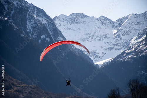 View of a person paragliding with snowy mountains in the background in Loudenvielle, France