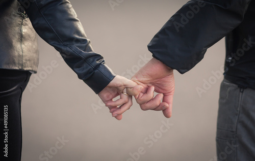 a couple of a girl and a guy hold hands, he holds her by the little finger, this is love and friendship. A young couple shares a warm, happy embrace