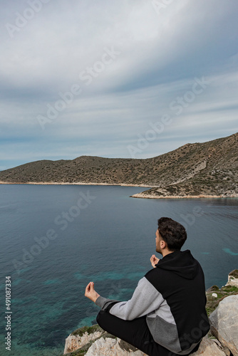 Back view of young man practices yoga and meditation on cliff. Lifestyle healthy man concept. Vertical banner.	
