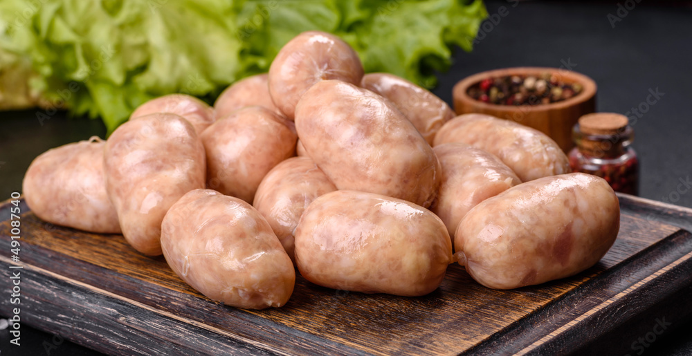 Raw sausages with ingredients on a cutting board on a stone background Raw sausages with ingredients on a cutting board on a stone background