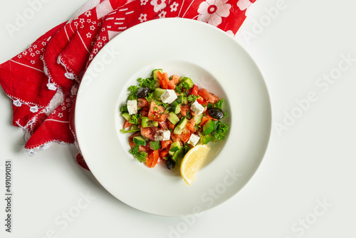 Turkish fresh Coban salad in a dish isolated on colorful table cloth top view on grey background mixed salad cucumber, lime,and tomato photo