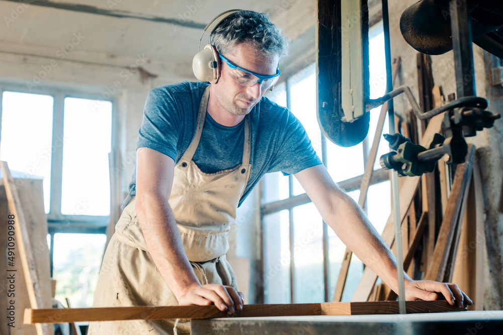 Diligent Carpenter on the band saw in his wood workshop Diligent Carpenter on the band saw in his wood workshop