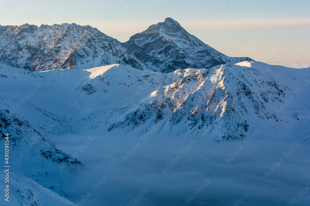 Obraz premium Winter landscape on a frosty sunny day. Clouds roll in the valley.