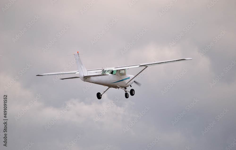 Avioneta branca a voar no céu, vista por trás, céu enublado