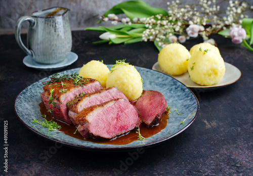 Traditionell gegrilltes Gourmet Entenbrust Filet mit Haut serviert mit Kartoffelknödeln in Dunkelbier Sauce als close-up auf einem Design Teller photo