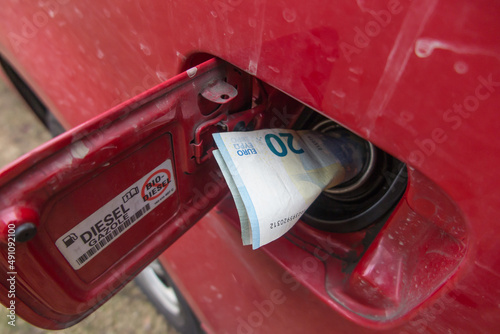 Banknotes, euro in the fuel filler of a red car.