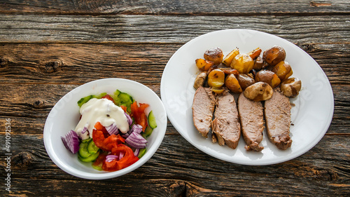 Roasted pork with potatoes and mushroom and salad on rustic wooden boards