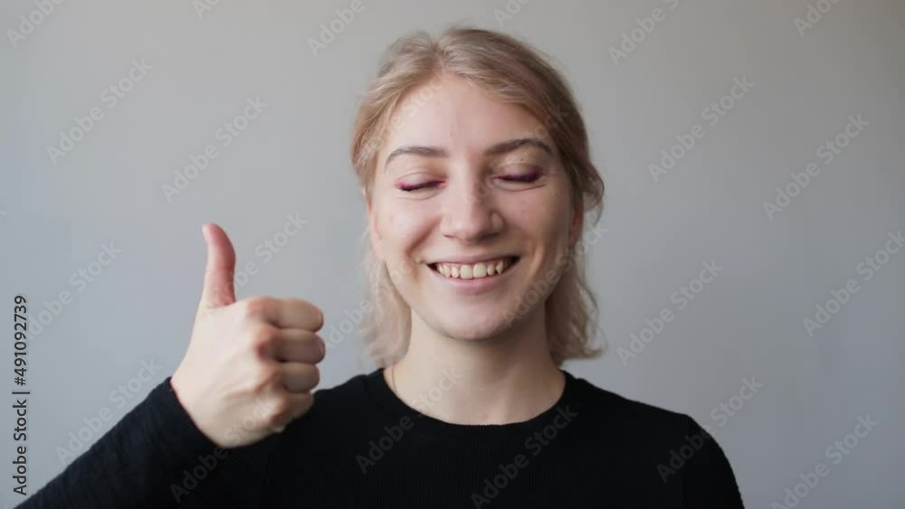 Happy young woman smiling and showing thumb up sign, looking at camera Happy young woman smiling and showing thumb up sign, looking at camera