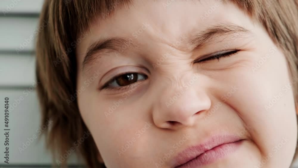 Close-up portrait of 5 year winking European boy. Pretty face with big brown eyes, snub nose. Child looking at camera. Good mood. Looks cute. Sincere emotions. Happy childhood concept. Fun grimace. Close-up portrait of 5 year winking European boy. Pretty face with big brown eyes, snub nose. Child looking at camera. Good mood. Looks cute. Sincere emotions. Happy childhood concept. Fun grimace.