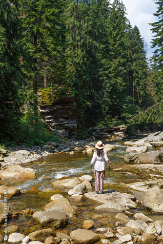 Woman - hiker near mountain river in forest. Carpathians. Ukraine.