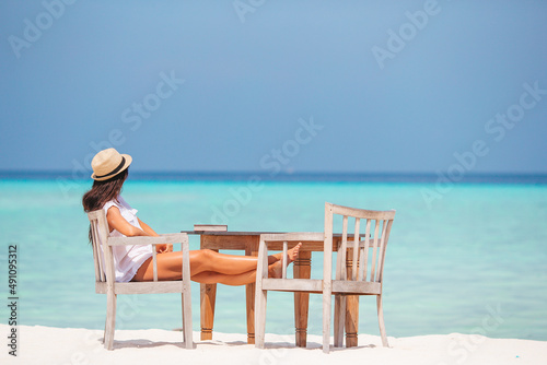 Young woman reading at outdoor beach cafe