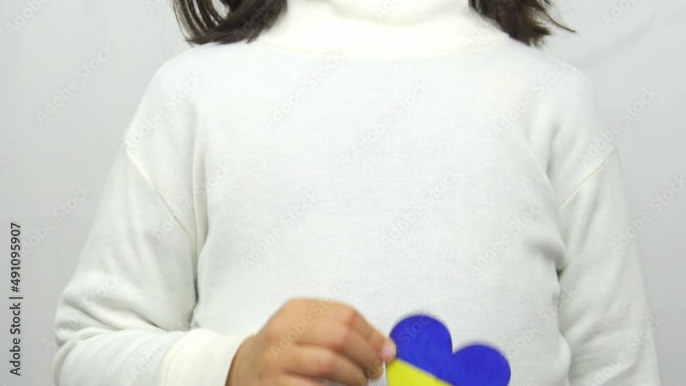 Child holding a heart with the Ukrainian flag. Child holding a heart with the Ukrainian flag.