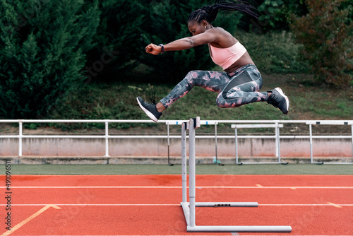 African-American athlete sprinter jumping a hurdle