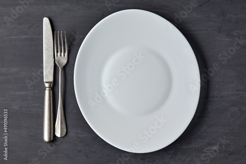 Oval white plate on a dark concrete background with cutlery