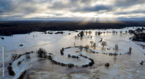 Fototapeta Naklejka Na Ścianę i Meble -  Aerial view to the sunrise colored floodplain with the frozen floodwater and river bends covered with old ice in Soomaa NP, Estonia