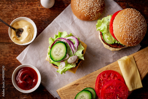 Cooking a hamburger. Stacking vegetables in a hamberger. The ingredients are different on a wooden background. Hamburger day.