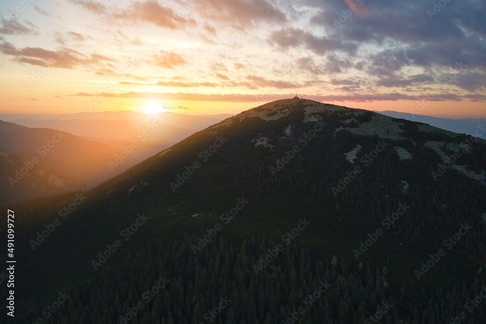 Aerial view of bright foggy morning over dark peak with mountain forest trees at autumn sunrise. Beautiful scenery of wild woodland at dawn Aerial view of bright foggy morning over dark peak with mountain forest trees at autumn sunrise. Beautiful scenery of wild woodland at dawn