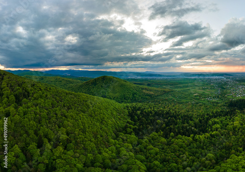 Aerial view of dark mountain hills covered with green mixed pine and lush forest in evening