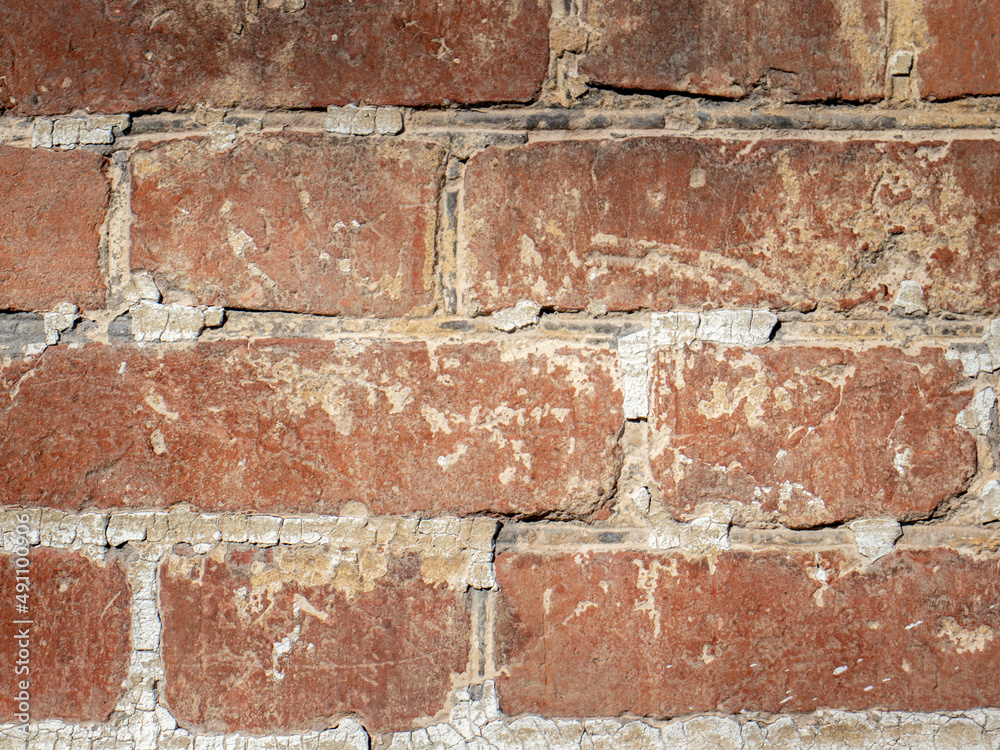 Fragment of old brickwork. Flat lay, close-up. Cracks and defects in the red brick on the wall are illuminated by bright light. Potholes and defects in red brick. Fragment of old brickwork. Flat lay, close-up. Cracks and defects in the red brick on the wall are illuminated by bright light. Potholes and defects in red brick.