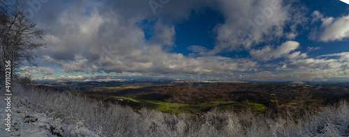 Wide panorama looking from Ostri vrh towards beautiful Radensko polje close to Grosuplje  Slovenia. Snow on the top  while green meadows at the bottom.