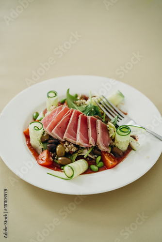 nicoise salad on a white plate with a fork