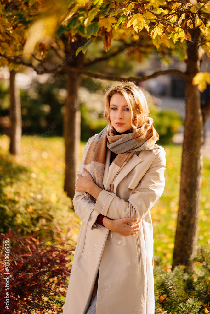 a portrait beautiful blonde in a coat with scarf on an autumn street.