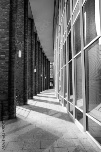 Urban modern street photography of architecture in Hamburg at a curved path between columns and glass windows and shadows on the ground