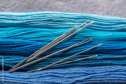 detalle de madeja de hilo para bordar en azules degradado con agujas y tijeras  photo