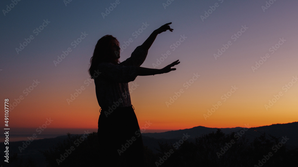 silhouette of carefree dancing girl at sunset 