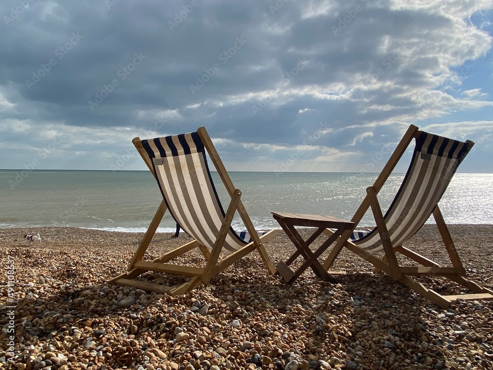 Deck chairs on seaside beach of seaside Hastings East Sussex Uk, sea sky and ocean waves behind