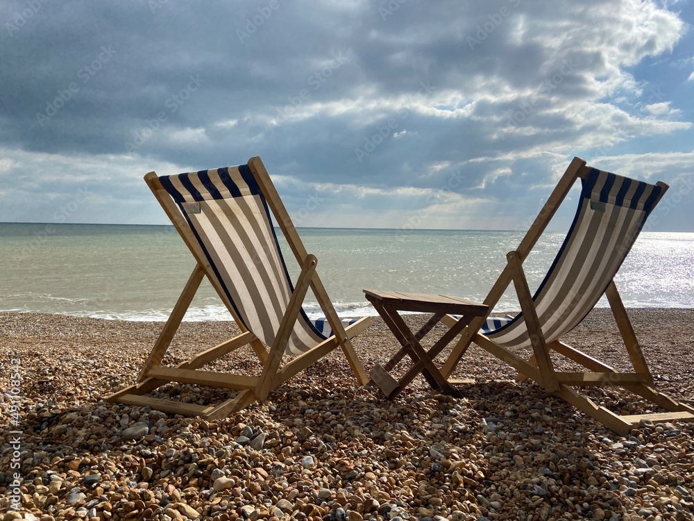 Deck chairs on seaside beach of seaside Hastings East Sussex Uk, sea sky and ocean waves behind