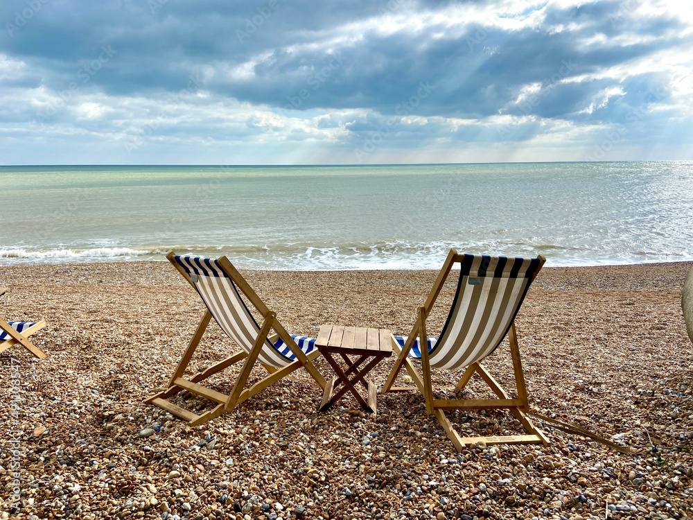 summer beach Deck chairs on seaside beach of summer seaside Hastings East Sussex Uk, sea sky and ocean waves behind