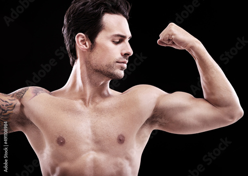 looking this good isnt easy.... Studio shot of a handsome bare-chested man flexing a bicep.