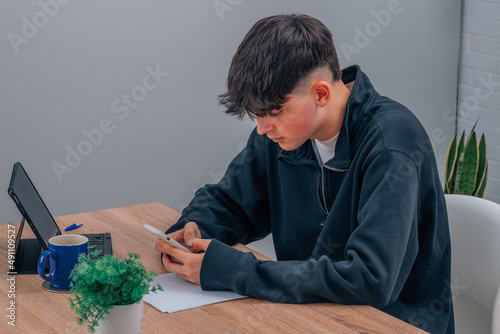 teenage student at desk with mobile phone