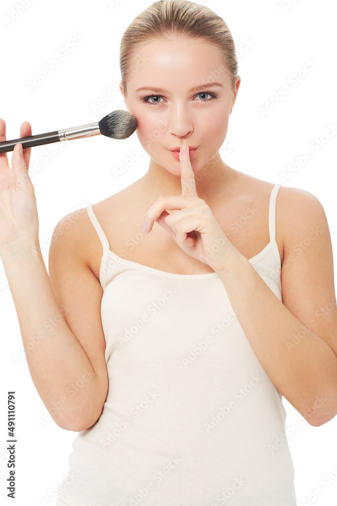 These are my beauty secrets.... A pretty woman putting a finger to her lips while applying blush to her face. These are my beauty secrets.... A pretty woman putting a finger to her lips while applying blush to her face.