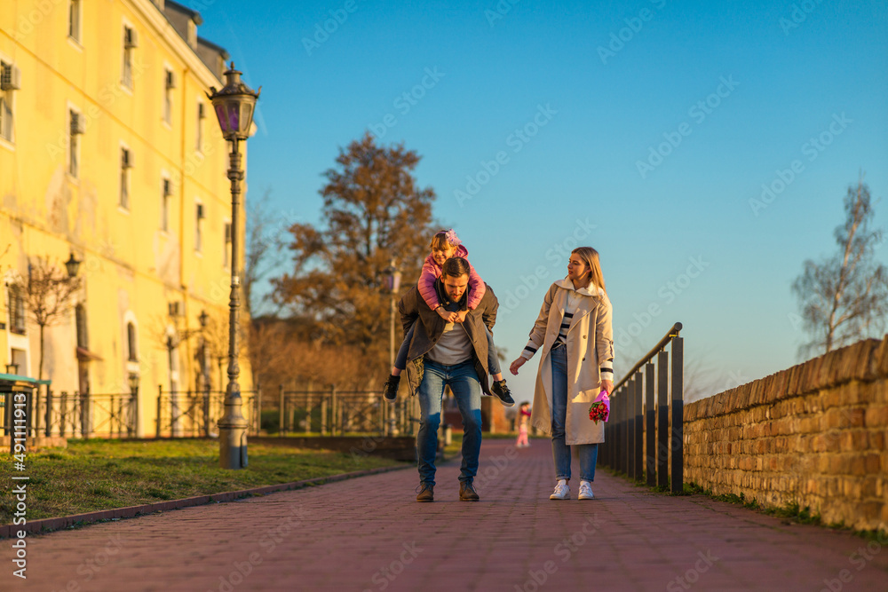 Obraz premium A happy three-member family walks and enjoys a beautiful winter day.