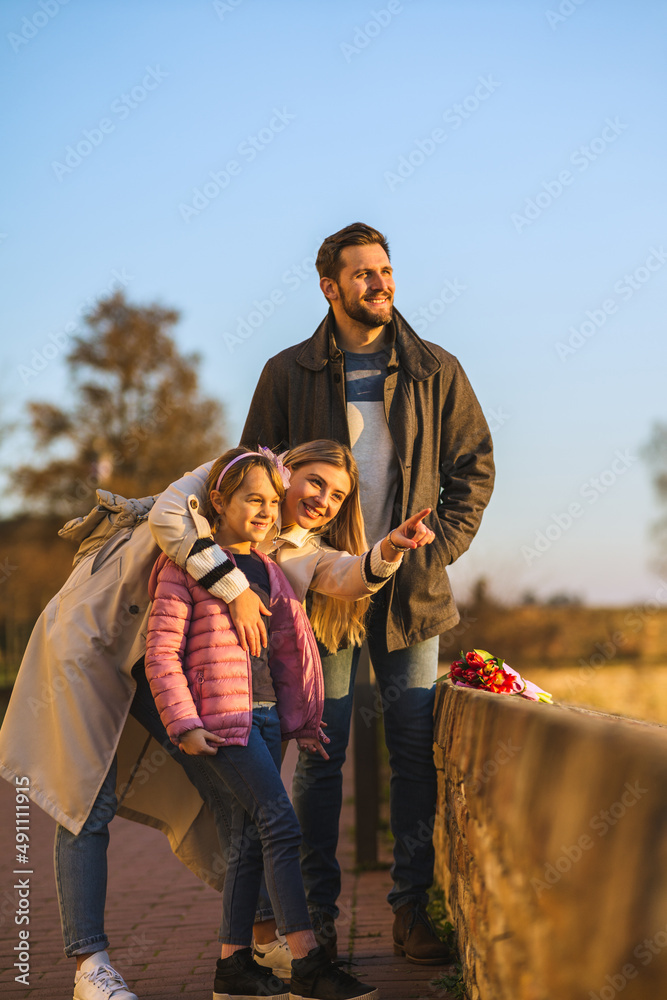 Fototapeta premium A happy family stands on a fortress overlooking the city and the river. They enjoy a beautiful day and a view.