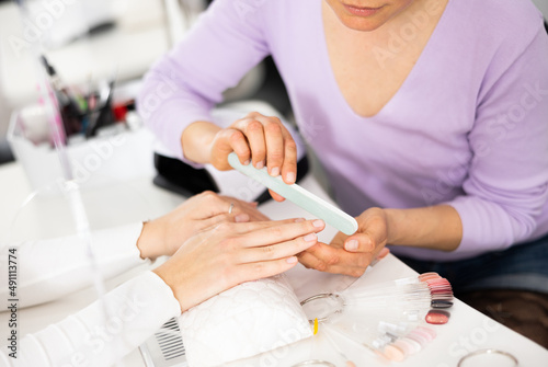 Woman hands in a nail salon  which the manicure master gives shape to the nails with a nail file. Close-up image