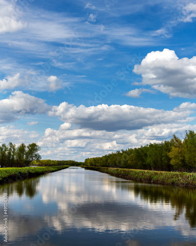 Landscape of a wetland conservation area with lakes reflecting cloudy skies and trees