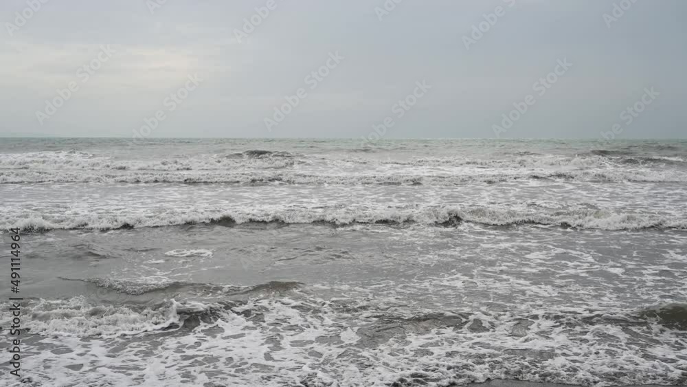 Muddy sea water after the rain. Stormy weather on the coast. Grey waves of the sea. Muddy sea water after the rain. Stormy weather on the coast. Grey waves of the sea.