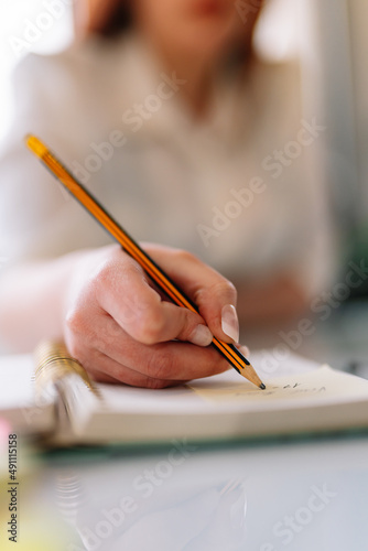 Young woman writing with pencil in notebook