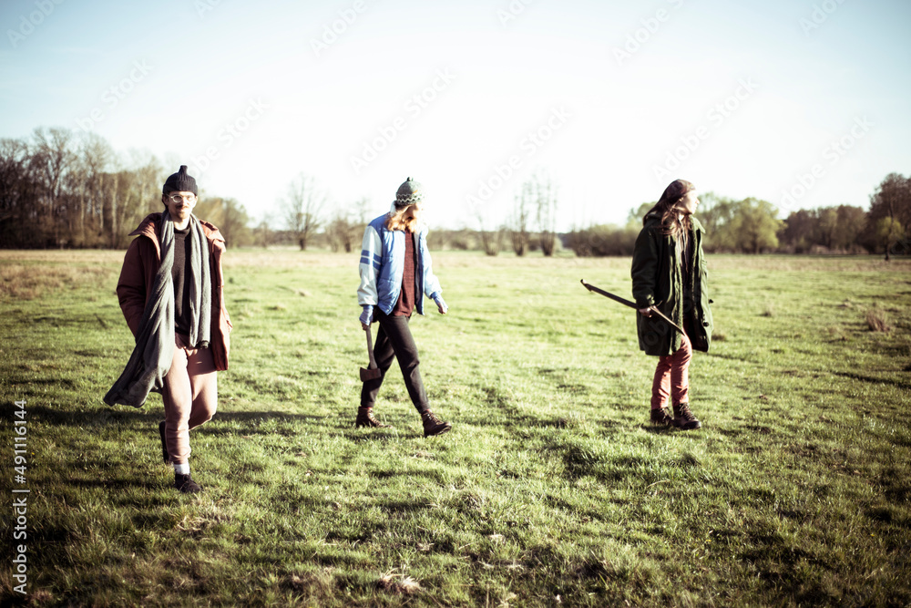 Friends stroll across grassy field in afternoon sun Friends stroll across grassy field in afternoon sun