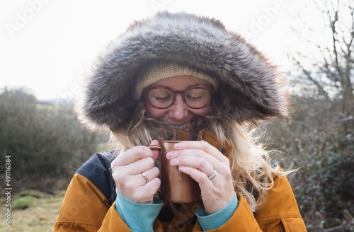 woman smiling keeping warm drinking a hot drink outside
