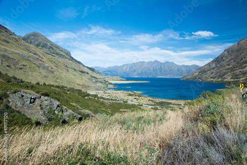 A blue lake surrounded by mountains and hill in summer, New Zealand