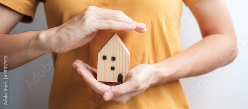 woman hand cover wooden Home model. real estate, insurance and property concepts