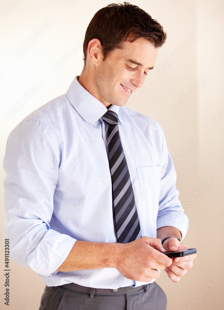 Texting a loved one. Smiling young businessman sending a text message. Texting a loved one. Smiling young businessman sending a text message.