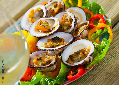 Appetizing baked in oven bivalve shellfishes (Dog cockles) served with vegetables on plate