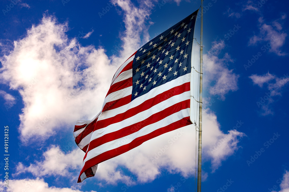 Obraz premium American flag against a blue sky with clouds