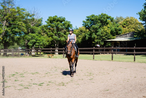 young latina woman in a stable riding a horse in the daytime, outdoor sports, horseback riding